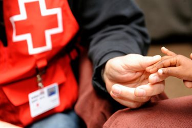 Red Cross worker holding a child's hand