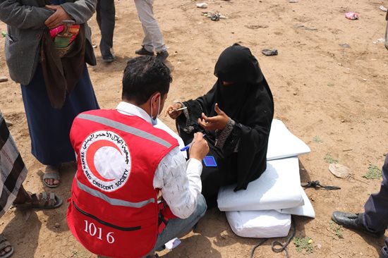 Un homme vêtu d’un dossard rouge et une femme portant des vêtements noirs sont assis sur le sol.