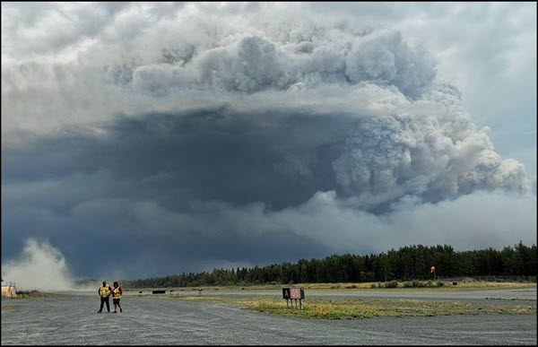 Des nuages et de la fumée planent au-dessus des membres de la communauté qui se préparent à évacuer les lieux en raison des feux de forêt au Manitoba.