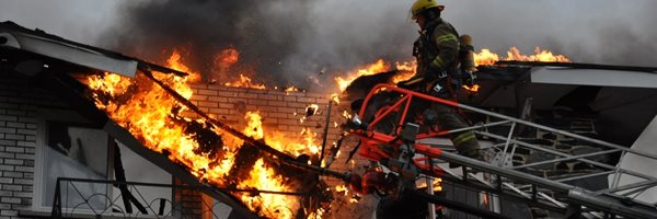 Un pompier sur le toit d'une demeure en feu