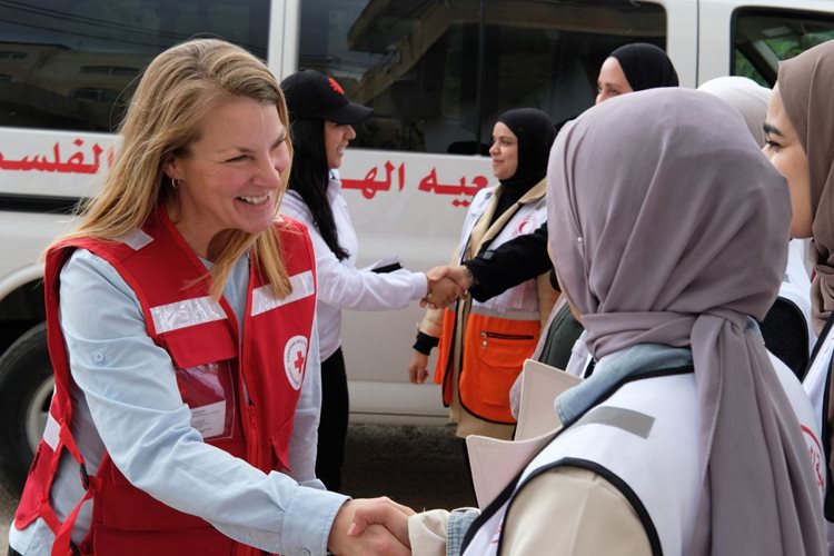 Kelsey Lemon sourit en serrant la main d’une bénévole de la Société du Croissant-Rouge palestinien.
