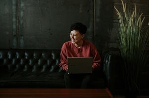 A smiling person holding a laptop